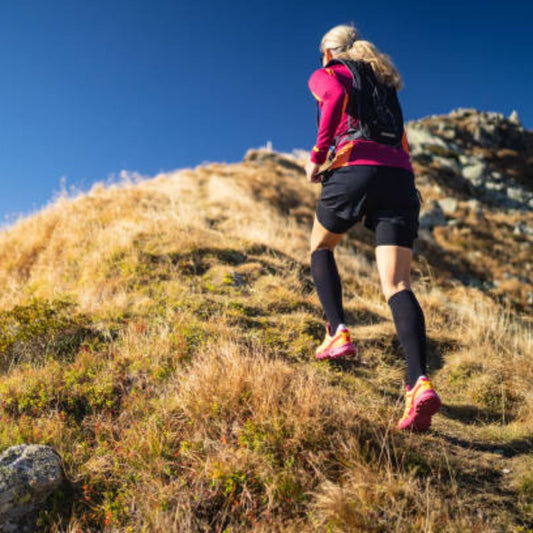 A woman running in the field while wearing black color color compression socks.