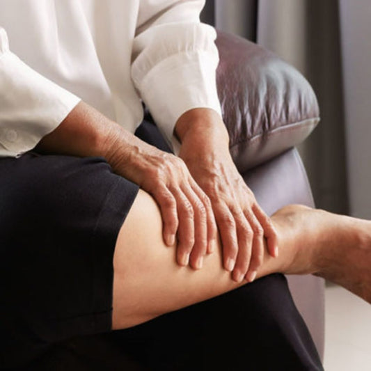 A woman sitting on the bed while massages her legs with slight edema.