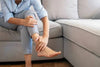 The image shows a woman experiencing foot and leg pain. Compression Socks with a Zipper Help Alleviate Foot Pain.