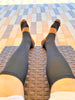 The image shows a man's legs sitting on a bench with stretch legs wearing black color copper infused compression socks.
